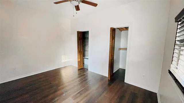 an empty room with wooden floor cabinet and windows
