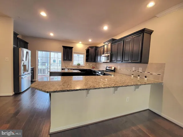 a kitchen with stainless steel appliances granite countertop a sink refrigerator and cabinets