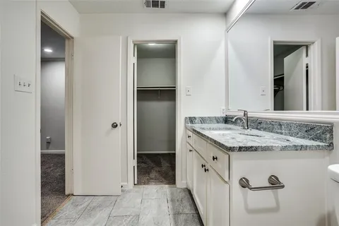 a spacious bathroom with a granite countertop sink and a mirror