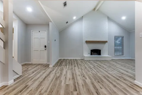 a view of empty room with wooden floor and fireplace