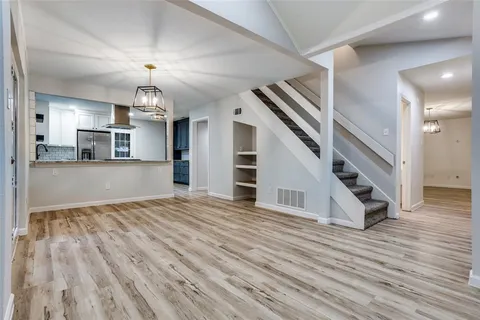 a view of a livingroom with wooden floor and stairs