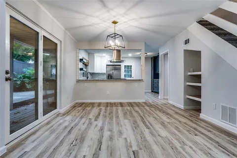 a view of large room with wooden floor kitchen view and windows