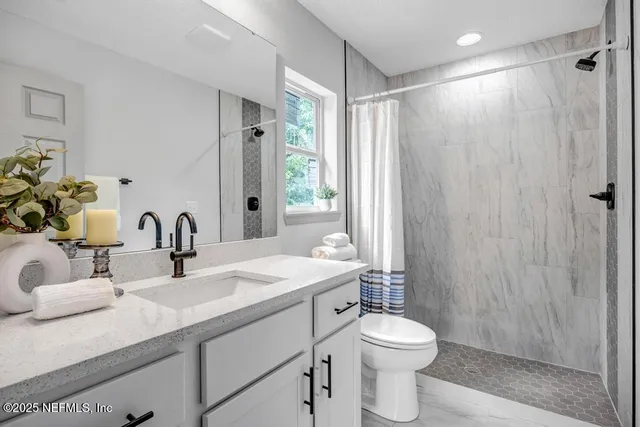 a bathroom with a sink a toilet and shower