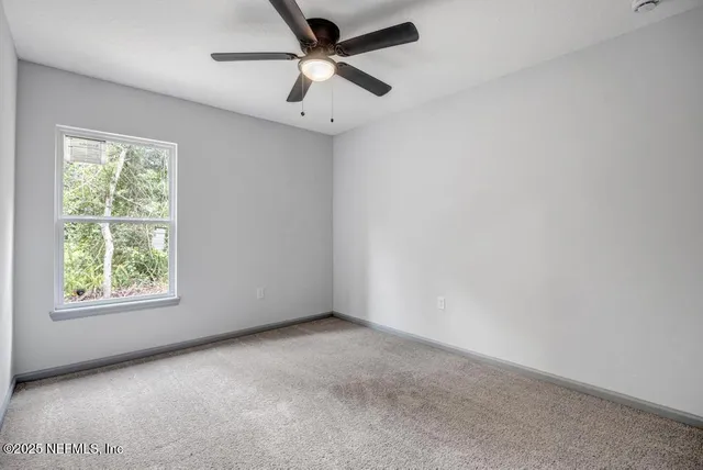 an empty room with a window and a fan
