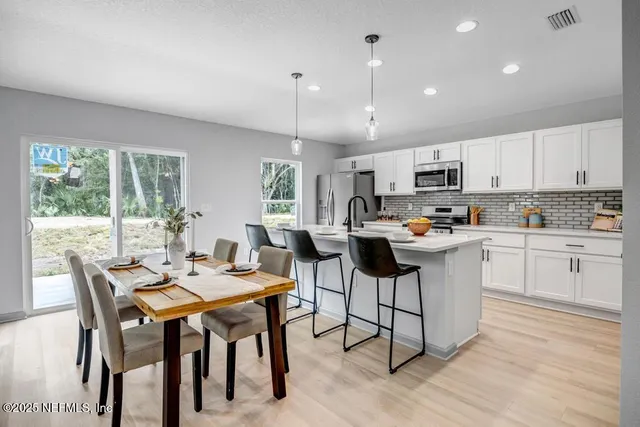a kitchen with a table chairs microwave and cabinets