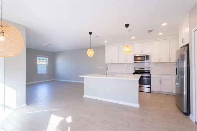 a large kitchen with cabinets a sink a window and stainless steel appliances