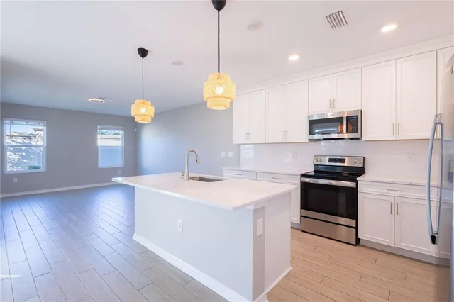 a kitchen with stainless steel appliances granite countertop a sink a stove and a wooden floors