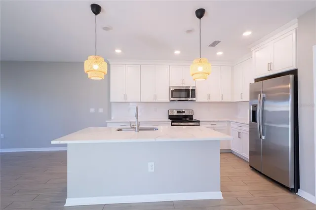 a kitchen with kitchen island white cabinets and stainless steel appliances