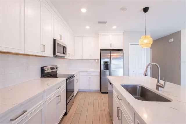 a kitchen with a sink dishwasher a stove top oven a refrigerator with island and cabinets