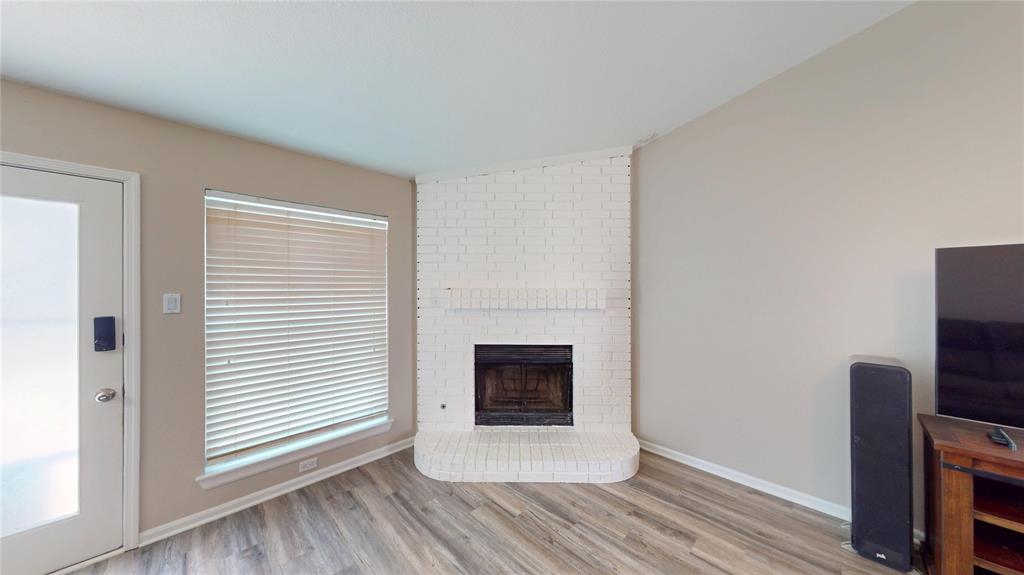 1317 Colonial Place Flower Mound, TX 75028 - Photo 5 of 20 Corner fireplace with a white painted brick surround and hearth, featuring a dark firebox