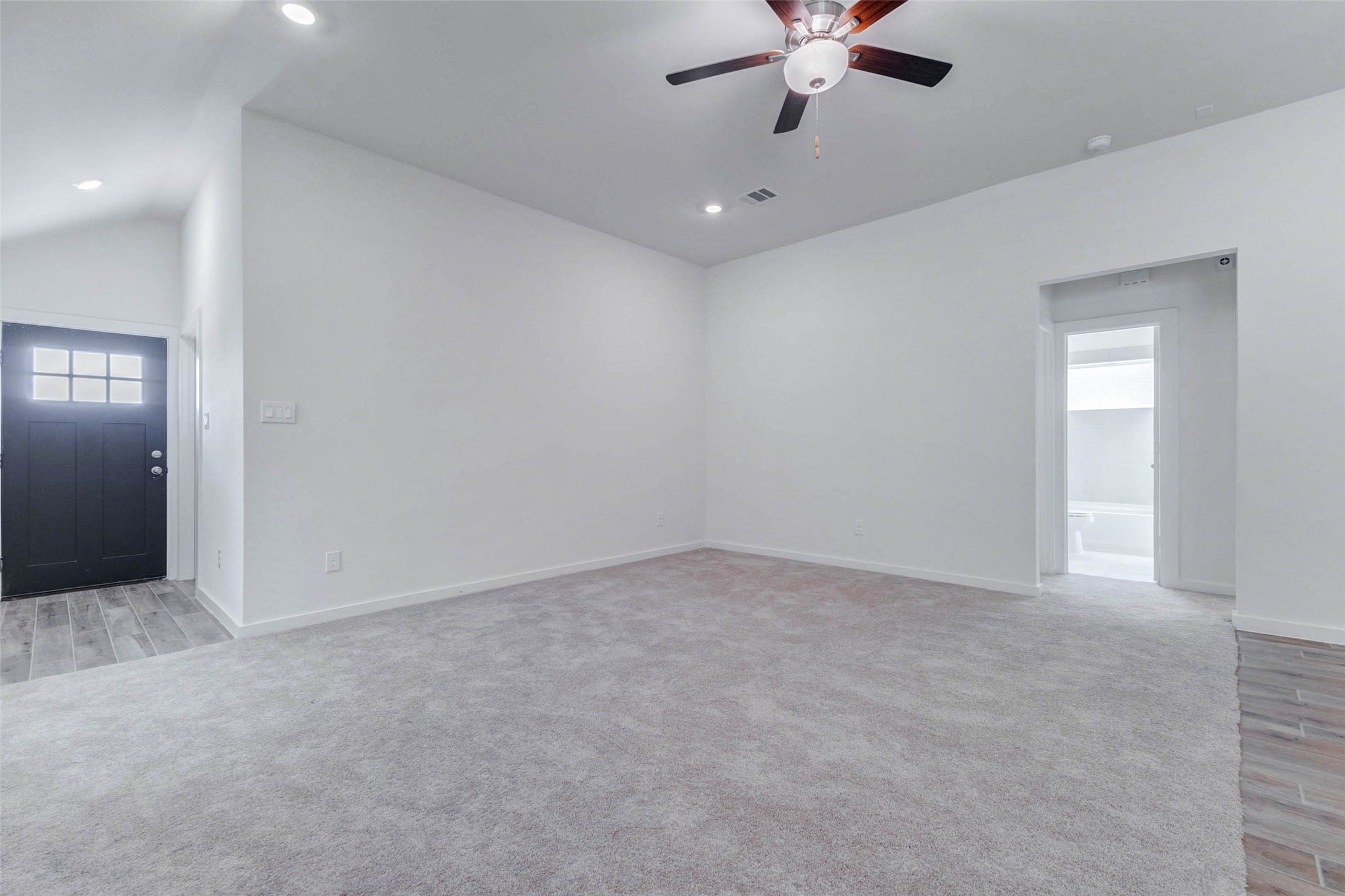 6467 Escondido Drive Rosharon, TX 77583 - Photo 10 of 32 Large family room view with plush carpet, high ceilings, ceiling fan, recessed lighting, and sightlines to the entry and adjoining spaces. The neutral walls and open layout create a flexible blank canvas for comfortable seating, media, décor, and personal style.