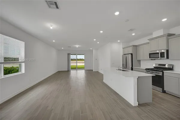 a view of kitchen with cabinets stainless steel appliances and wooden floor