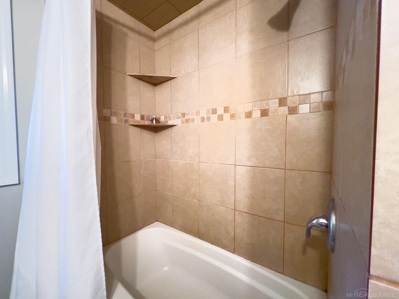 1123 Radov Road Gladwin, MI 48624 - Photo 12 of 29 Decorative tile in the shower/tub complete with built in shelving for all your showing products.
