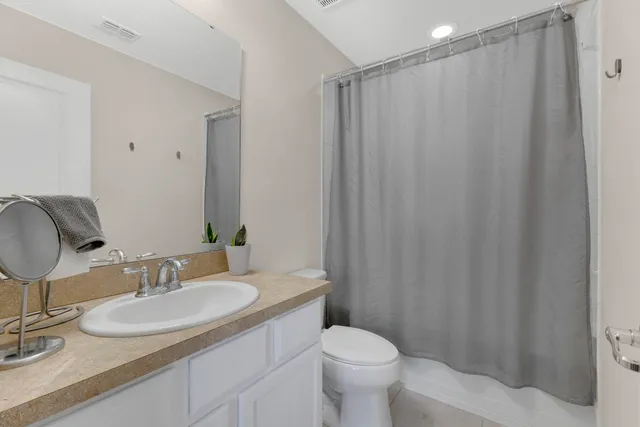 a bathroom with a granite countertop sink toilet and a mirror
