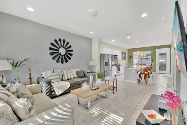 a living room with furniture and kitchen view with potted plants
