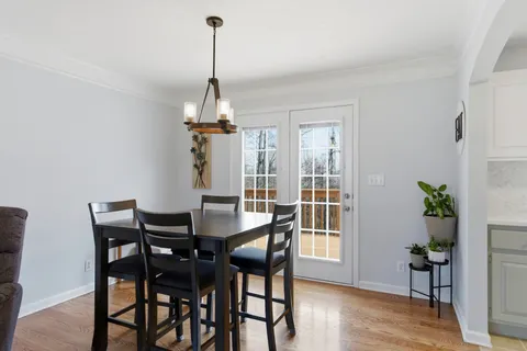 a dining room with furniture wooden floor a chandelier and a window