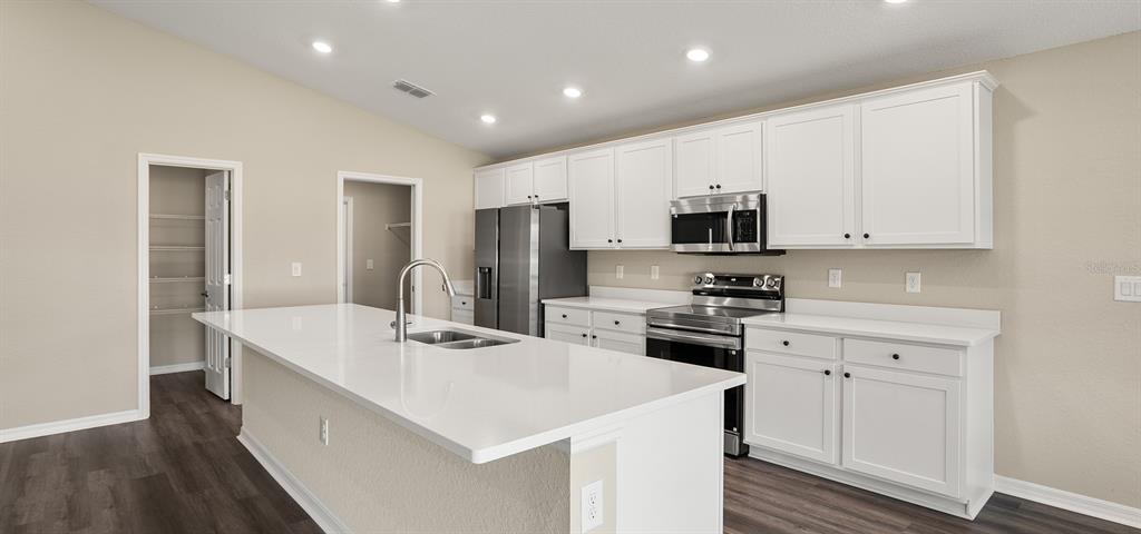 7654 Southwest 6th Loop Ocala, FL 34474 - Photo 14 of 28 a kitchen that has a lot of white cabinets and stainless steel appliances