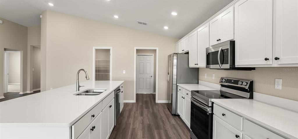 7654 Southwest 6th Loop Ocala, FL 34474 - Photo 17 of 28 a kitchen with stainless steel appliances a sink dishwasher a refrigerator and a stove with wooden floor