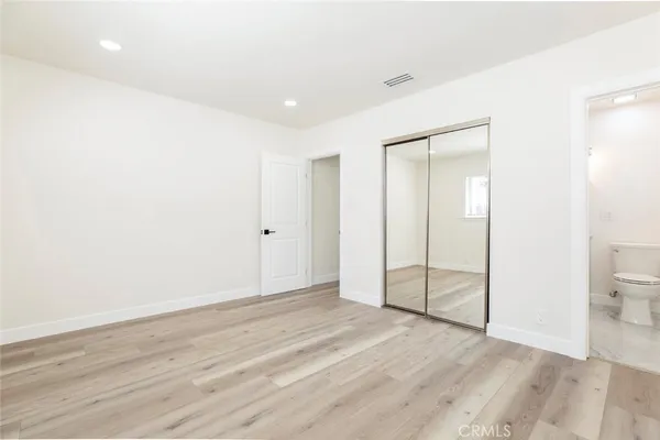 an empty room with wooden floor and a toilet