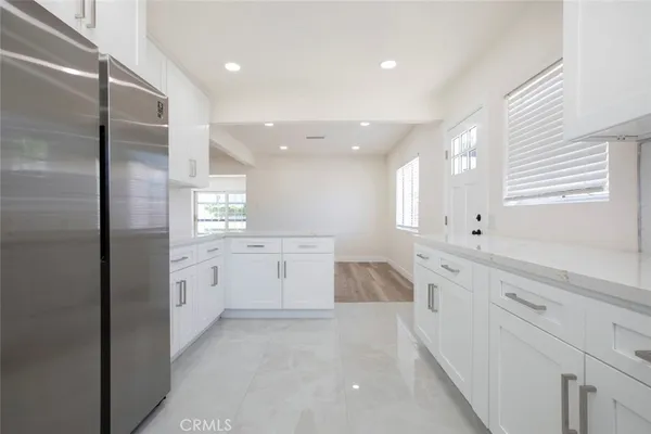 a large white kitchen with center island and stainless steel appliances