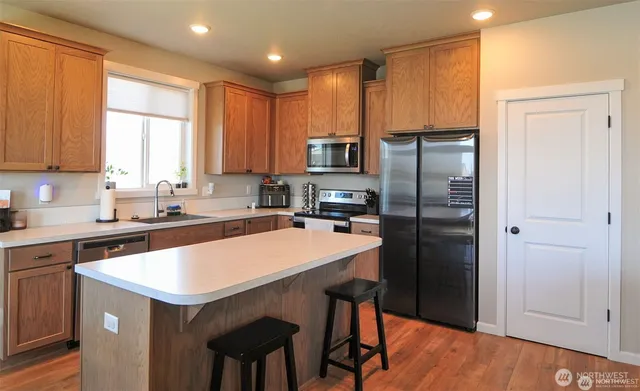 a kitchen with a refrigerator a sink dishwasher and a stove with wooden floor