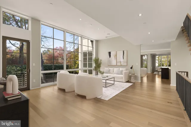 a living room with furniture large windows and wooden floor
