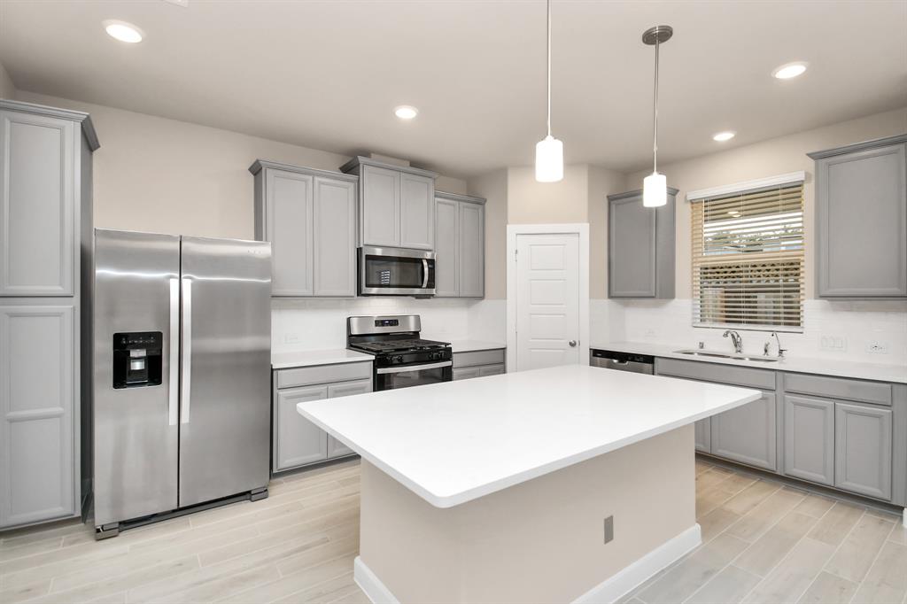 a kitchen with a white center island a sink cabinets and stainless steel appliances