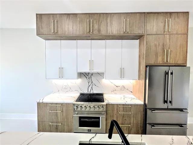 a kitchen with granite countertop a stove and a refrigerator with cabinets
