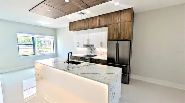 a kitchen with stainless steel appliances granite countertop a sink a refrigerator and a stove