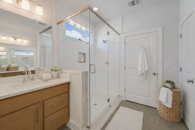 a spacious bathroom with a double vanity sink a mirror and a shower