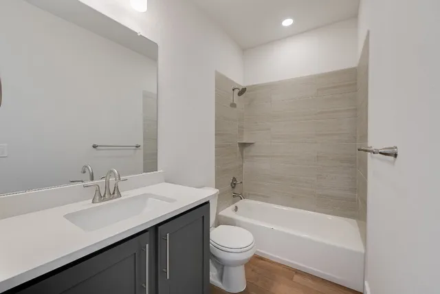 a bathroom with a bathtub shower sink vanity mirror and toilet