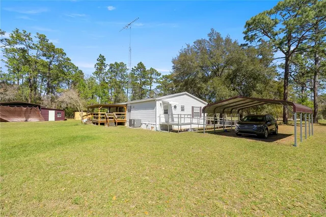 a view of a house with pool and trees in the background