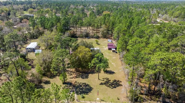 an aerial view of residential house with outdoor space and trees all around