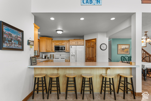 1340 Trapper Loop Garden City, UT 84028 - Photo 11 of 35 Kitchen with white appliances, a peninsula, light countertops, recessed lighting, and a kitchen bar