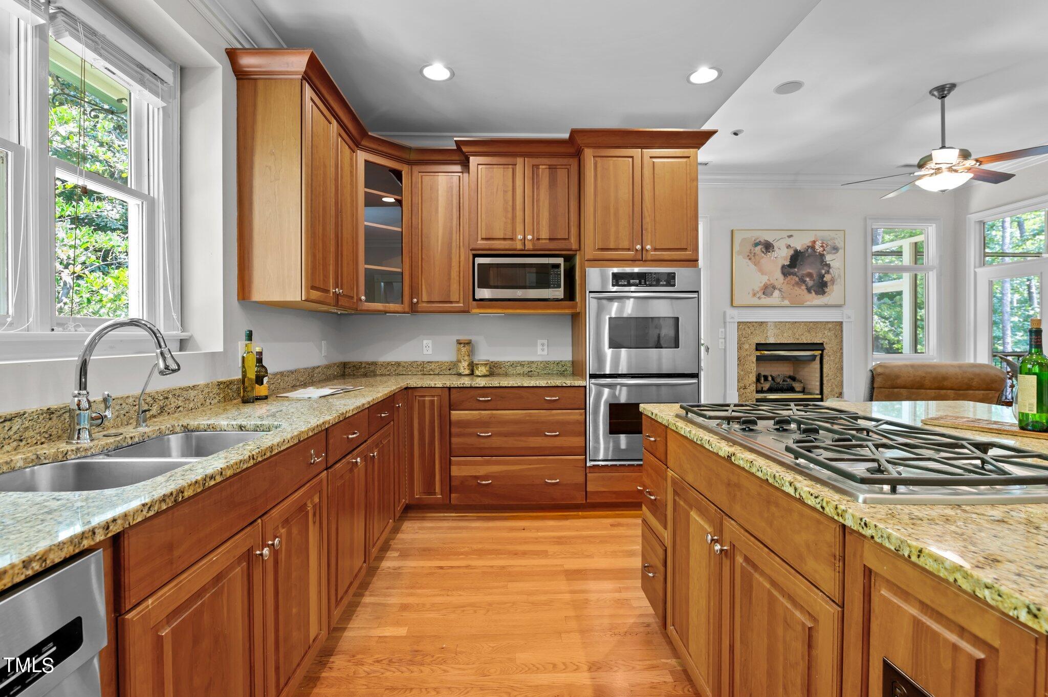 11112 Brass Kettle Road Raleigh, NC 27614 - Photo 24 of 65 a kitchen with stainless steel appliances granite countertop a stove top oven a sink dishwasher a dining table and chairs with wooden floor