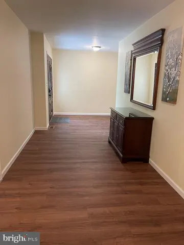 a view of an empty room with wooden floor and a mirror