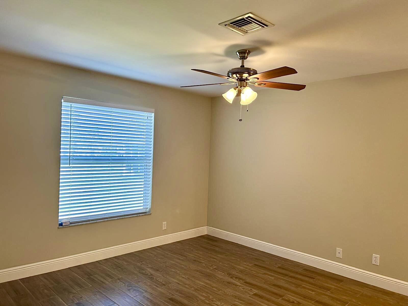 2811 Southwest 15th Street, Unit 202 Delray Beach, FL 33445 - Photo 13 of 21 an empty room with wooden floor fan and windows