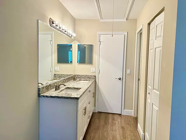 a bathroom with a granite countertop sink a mirror and shower
