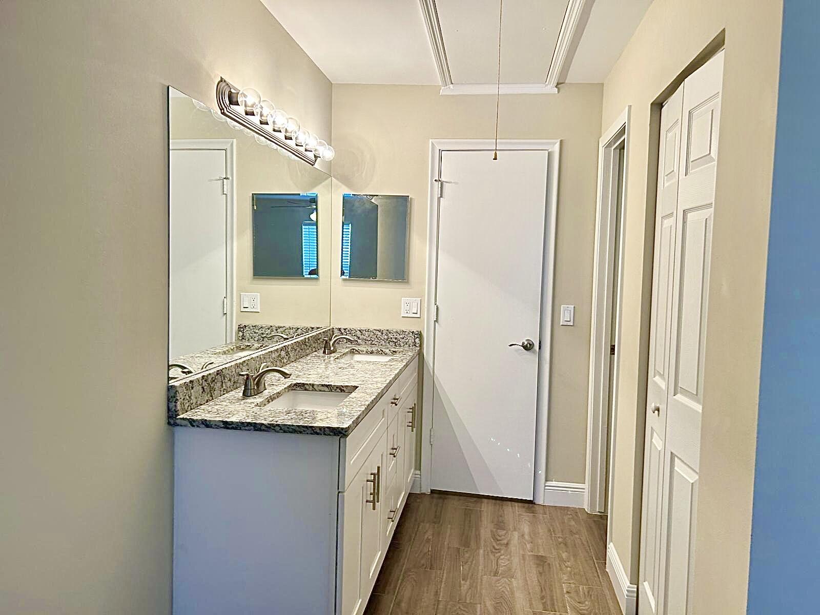 2811 Southwest 15th Street, Unit 202 Delray Beach, FL 33445 - Photo 15 of 21 a bathroom with a granite countertop sink a mirror and shower