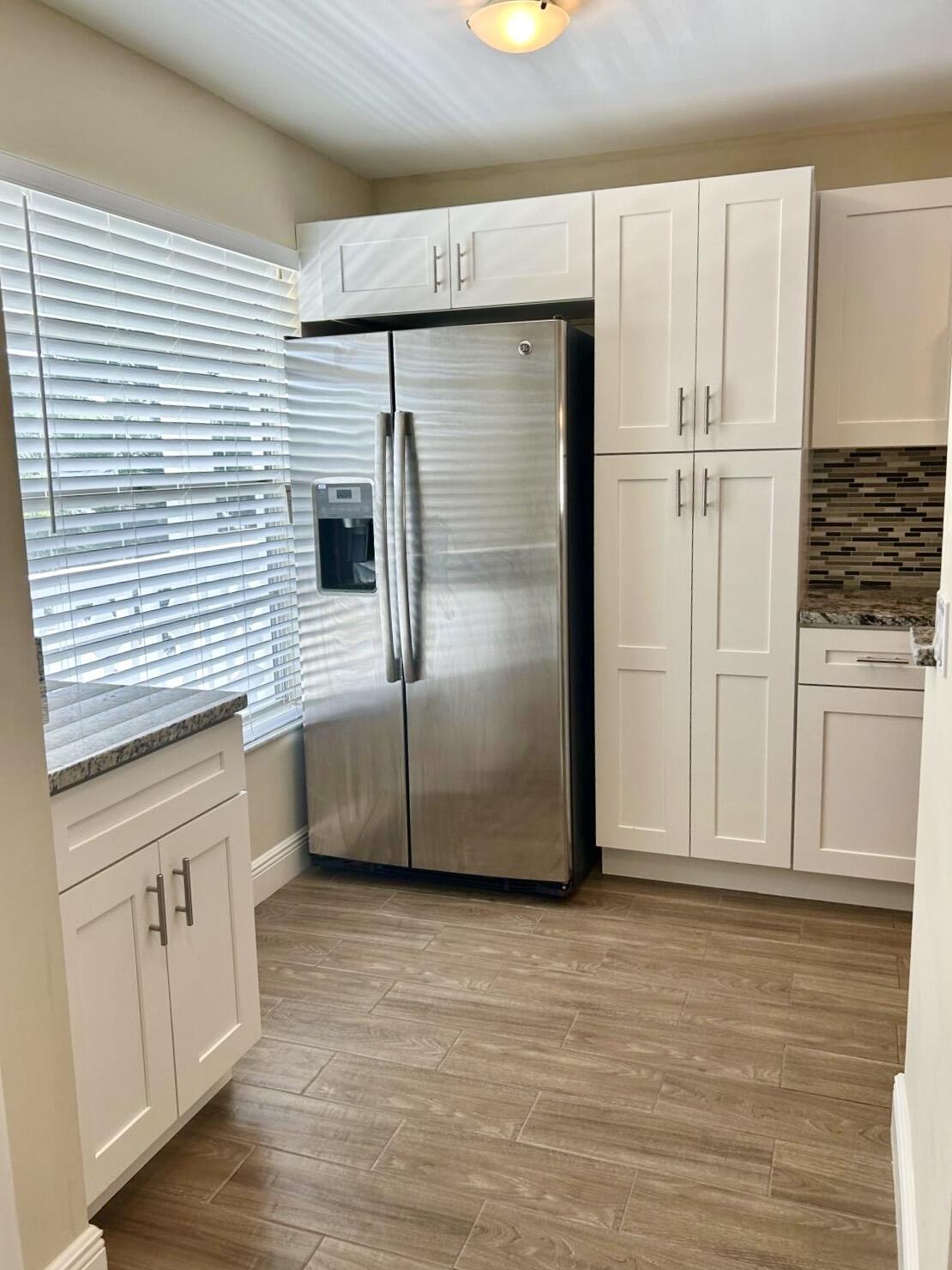 2811 Southwest 15th Street, Unit 202 Delray Beach, FL 33445 - Photo 5 of 21 a kitchen with stainless steel appliances wooden floor and staircase