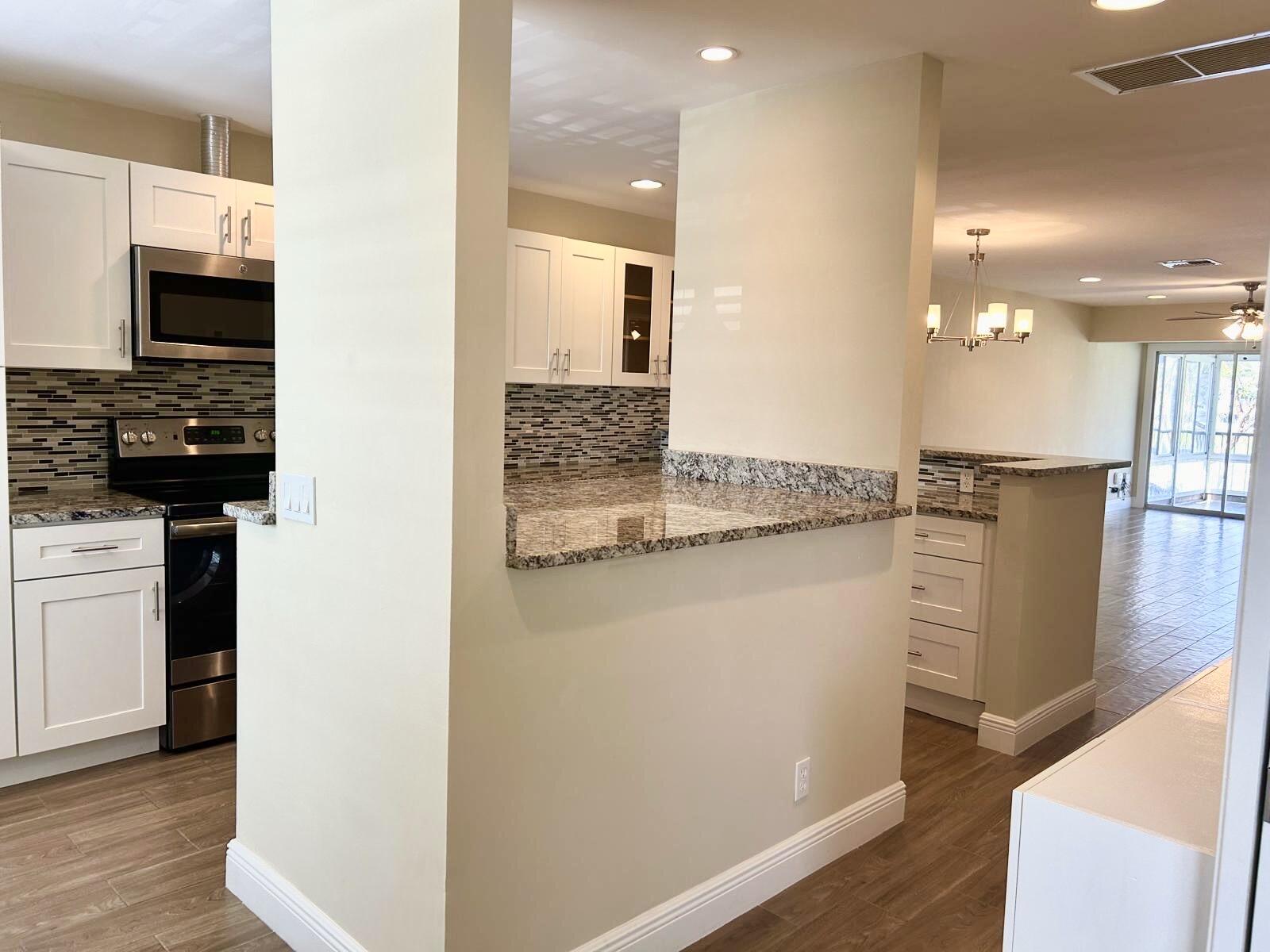 2811 Southwest 15th Street, Unit 202 Delray Beach, FL 33445 - Photo 7 of 21 a kitchen with kitchen island granite countertop a refrigerator and a stove