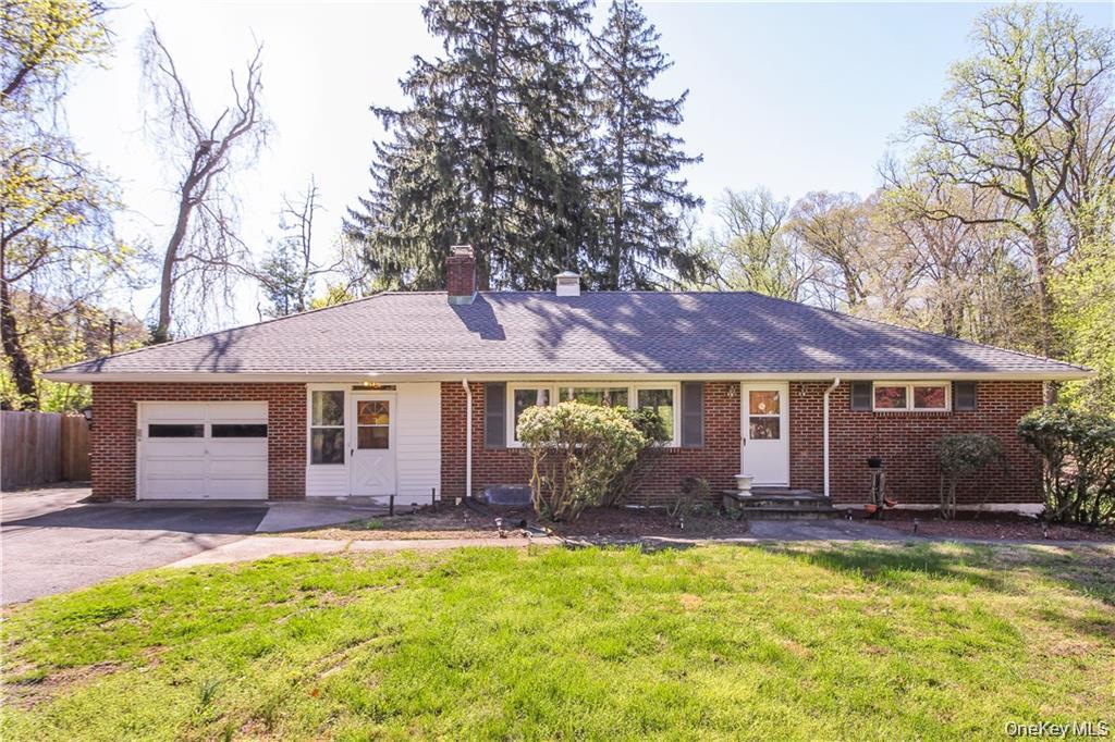 Ranch-style house with brick siding, a chimney, asphalt driveway, a garage, and roof with asphalt shingles.