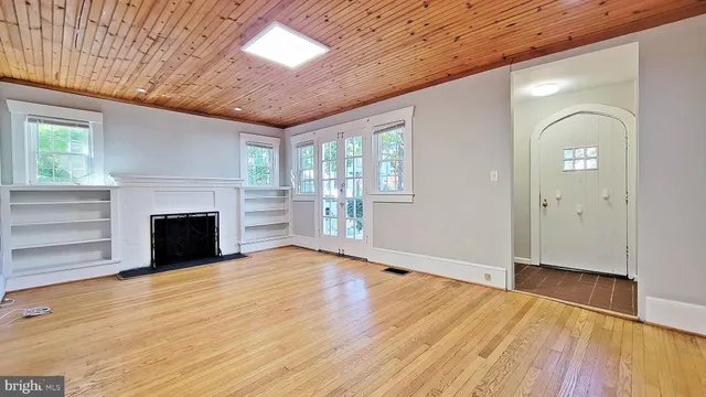 a view of an empty room with wooden floor fireplace and a window