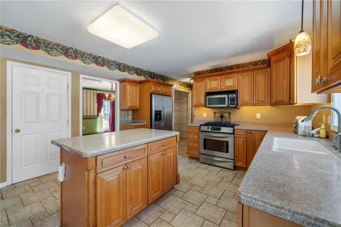 a kitchen with stainless steel appliances granite countertop a stove top oven a sink dishwasher a dining table and chairs with wooden floor