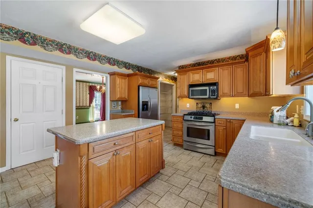 a kitchen with stainless steel appliances granite countertop a stove top oven a sink dishwasher a dining table and chairs with wooden floor