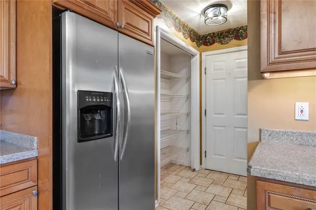 a view of a refrigerator in kitchen and an empty room