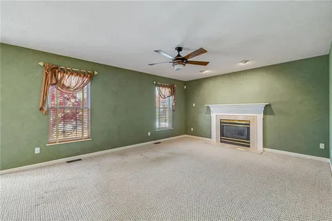 an empty room with windows and fireplace