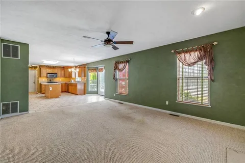 a furnished livingroom with windows and chandelier fan