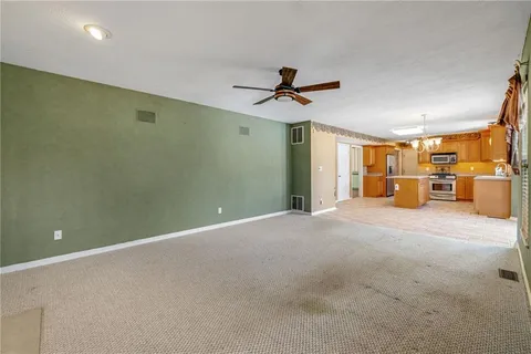 a view of a livingroom with a chandelier fan and windows