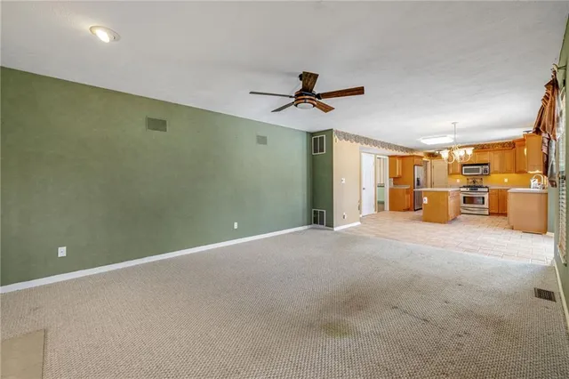 a view of a livingroom with a chandelier fan and windows